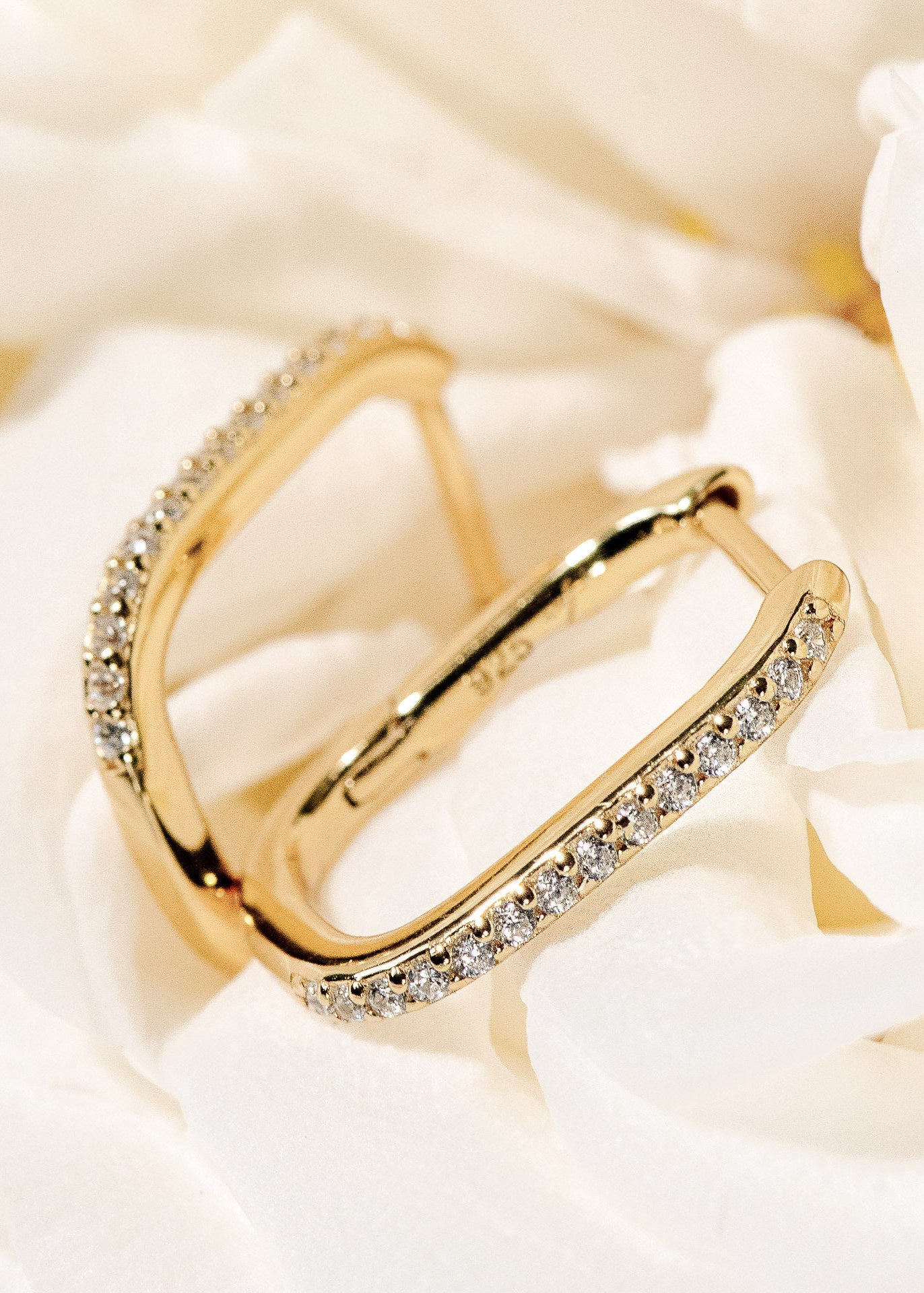 Twentyfour, ovale dezente und verschlossene Creolen besetzt mit Zirkonia Steinen und bestehen aus 18 Karat vergoldung und 925 Sterlingsilber von Mobijou platziert in einer weißen Rose