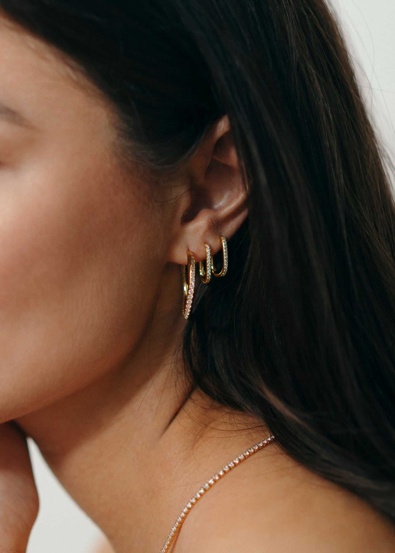 Tragebild mit Twentyfour, ovale dezente und verschlossene Creolen besetzt mit Zirkonia Steinen und bestehen aus 18 Karat vergoldung und 925 Sterlingsilber von Mobijou