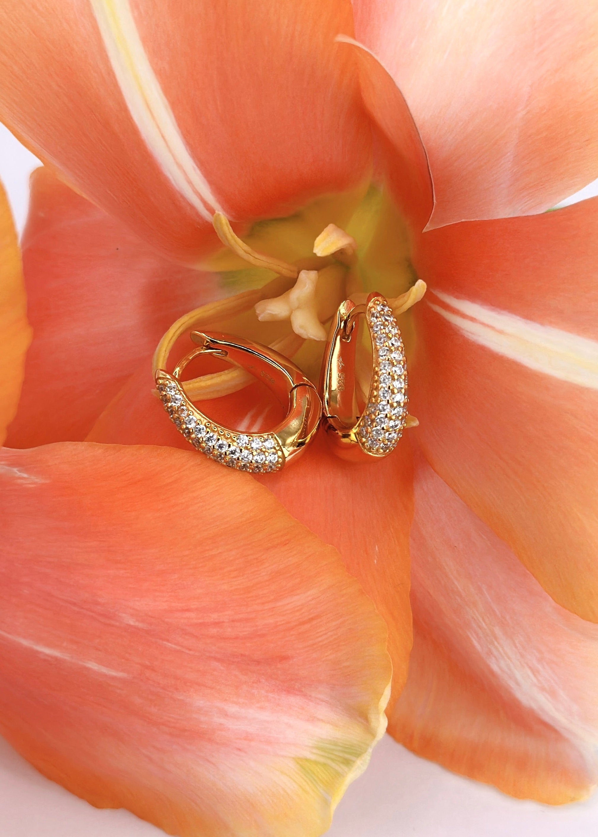 Goldene Creolen Meraki besetzt mit Zirkonia Steinen und bestehen aus 18 Karat Vergoldung und Sterlingsilber, platziert in einer orangenen Blume